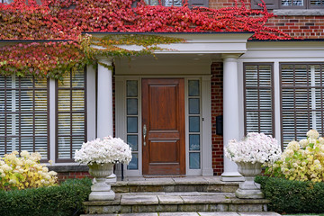 Large brick house with poritco entrance and colorful ivy in fall