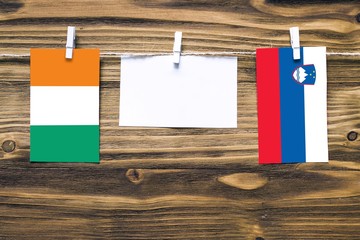 Hanging flags of Cote D'Ivoire and Slovenia attached to rope with clothes pins with copy space on...