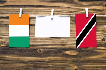 Hanging flags of Cote D'Ivoire and Trinidad And Tobago attached to rope with clothes pins with copy...