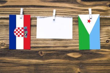 Hanging flags of Croatia and Djibouti attached to rope with clothes pins with copy space on white note paper on wooden background.Diplomatic relations between countries.