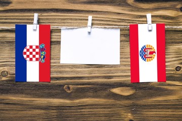Hanging flags of Croatia and French Polynesia attached to rope with clothes pins with copy space on...