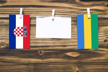Hanging flags of Croatia and Gabon attached to rope with clothes pins with copy space on white note...