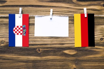Hanging flags of Croatia and Germany attached to rope with clothes pins with copy space on white...