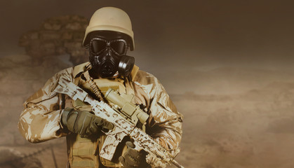 Fully equipped soldier with rifle and gas mask standing in deset dust storm background.
