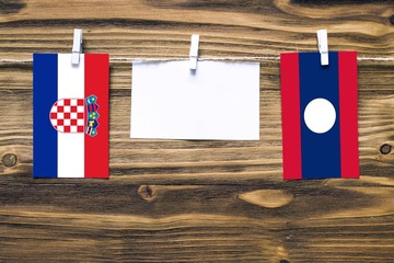 Hanging flags of Croatia and Laos attached to rope with clothes pins with copy space on white note...