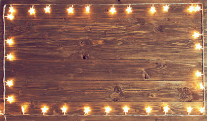 Merry Christmas! Christmas lights frame on wooden background with copy space