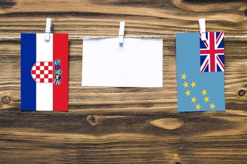 Hanging flags of Croatia and Tuvalu attached to rope with clothes pins with copy space on white...