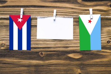 Hanging flags of Cuba and Djibouti attached to rope with clothes pins with copy space on white note...