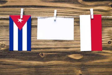 Hanging flags of Cuba and Indonesia attached to rope with clothes pins with copy space on white...
