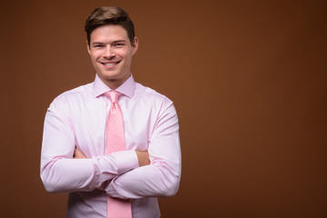 Studio shot of young handsome businessman with pink shirt