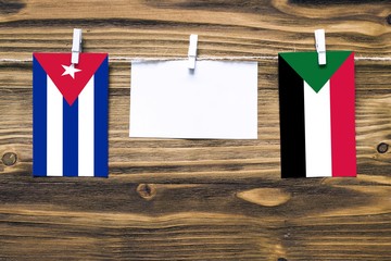 Hanging flags of Cuba and Sudan attached to rope with clothes pins with copy space on white note...
