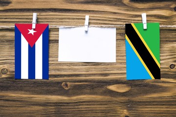 Hanging flags of Cuba and Tanzania attached to rope with clothes pins with copy space on white note...