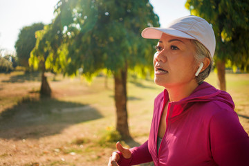 attractive middle aged woman running happy at city park . beautiful and sporty lady on her 40s exercising doing jogging workout on a sunny morning enjoying