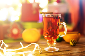 Mulled wine with spices and Christmas tree on wooden background