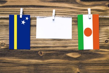 Hanging flags of Curacao and Niger attached to rope with clothes pins with copy space on white note...