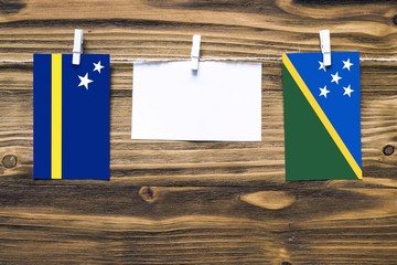 Hanging flags of Curacao and Solomon Islands attached to rope with clothes pins with copy space on...