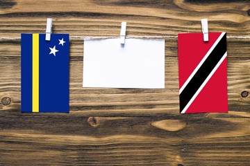 Hanging flags of Curacao and Trinidad And Tobago attached to rope with clothes pins with copy space...