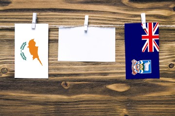Hanging flags of Cyprus and Falkland Islands attached to rope with clothes pins with copy space on...