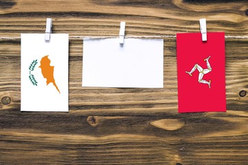 Hanging flags of Cyprus and Isle Of Man attached to rope with clothes pins with copy space on white...