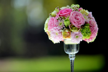 A large bouquet of flowers and colorful in a clear glass vase on a blurred green background, Used in wedding ceremonies.