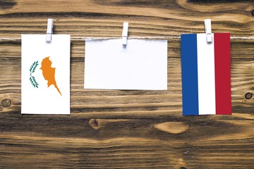 Hanging flags of Cyprus and Netherlands attached to rope with clothes pins with copy space on white note paper on wooden background.Diplomatic relations between countries.