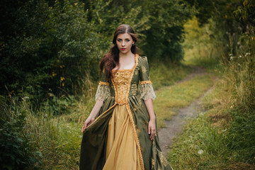 Beautiful young girl in a green rococo dress, walk through the park. A model with clean skin.