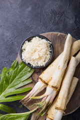 Fresh orgaanic horseradish or Horse-radish root on wooden cutting board.  top view