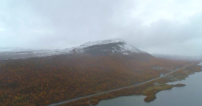 Saana mountain, Aerial, tracking, drone shot, overlooking the saanatunturi fell, the Kilpisjarvi lake and e8 road, on a foggy, autumn day, in Enontekio, Finland