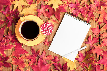 cup with black coffee, red lollipops, white notepad, pen on wooden table with autumn fallen yellow, orange, red leaves Flat lay Top view Mock up Hello september, october, november, sesonal concept