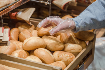 A young woman takes from the counter in the supermarket fresh bread .