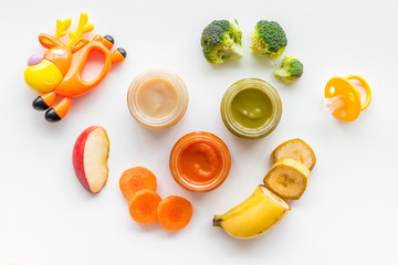 Baby food. Colorful puree in glass jars near vegetables and fruits on white background top view