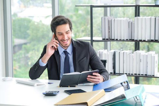 The image of a business man at a desk using a telephone