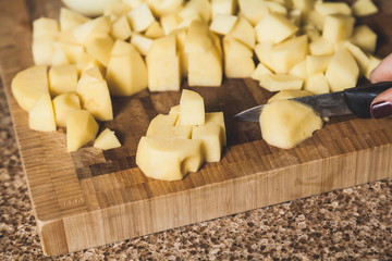 Diced peeled potatoes lies on cutting board