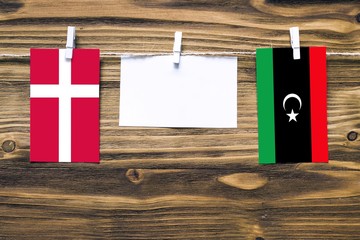 Hanging flags of Denmark and Libya attached to rope with clothes pins with copy space on white note...