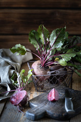 Fresh organic red beets with leaves in a wicker basket on a wooden table. Natural organic...