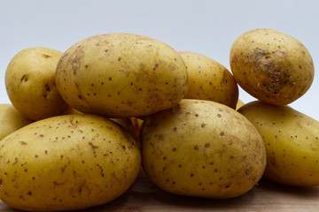 Potatoes on wooden table, white background