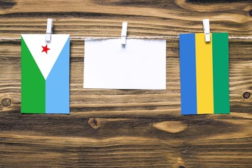 Hanging flags of Djibouti and Gabon attached to rope with clothes pins with copy space on white...