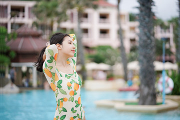 Woman in swimming suit posing near the pool and smile.