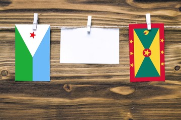 Hanging flags of Djibouti and Grenada attached to rope with clothes pins with copy space on white...