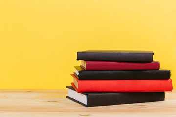 Simple composition of many hardback books, raw of books on wooden table and pastel yellow background