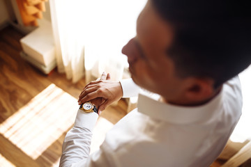 Men's wrist watch, the man is watching the time. Businessman clock, businessman checking time on his wristwatch. Groom's hands in a suit adjusting wristwatch, wedding preparations, groom accessories.