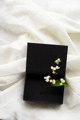 Fototapeta na wymiar wild white flower in classy black gift box on beige white soft fabric background