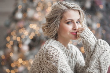 Beautiful blond woman on christmas background. Beauty near cristmas tree. Close up portrait of...
