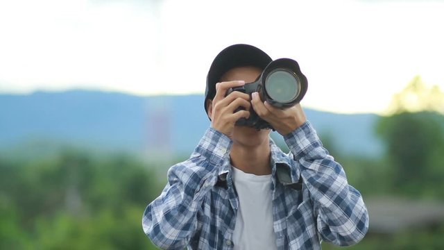 Young asian photographer shooting a picture of nature and smiling with happiness