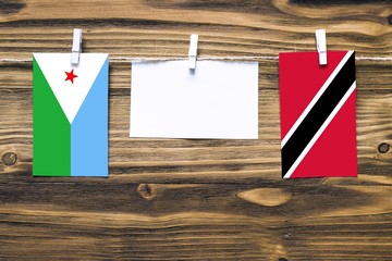 Hanging flags of Djibouti and Trinidad And Tobago attached to rope with clothes pins with copy...