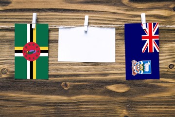 Hanging flags of Dominica and Falkland Islands attached to rope with clothes pins with copy space...