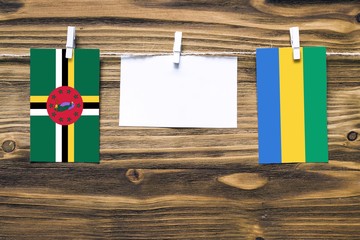 Hanging flags of Dominica and Gabon attached to rope with clothes pins with copy space on white...