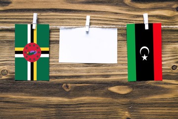 Hanging flags of Dominica and Libya attached to rope with clothes pins with copy space on white...