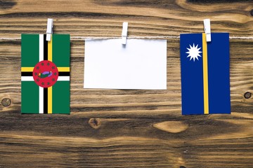 Hanging flags of Dominica and Nauru attached to rope with clothes pins with copy space on white...