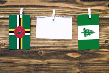 Hanging flags of Dominica and Norfolk Island attached to rope with clothes pins with copy space on...